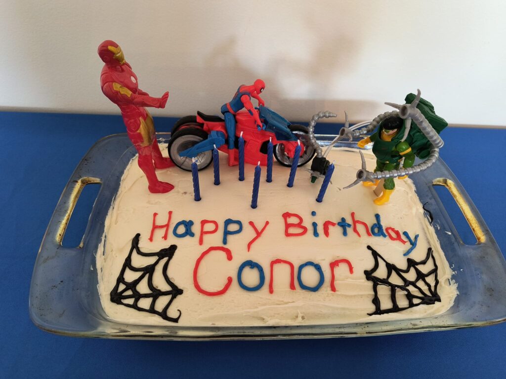 Spiderman birthday cake homemade with Spiderman action figure on motorcycle and his friends Doc Oc and Iron Man