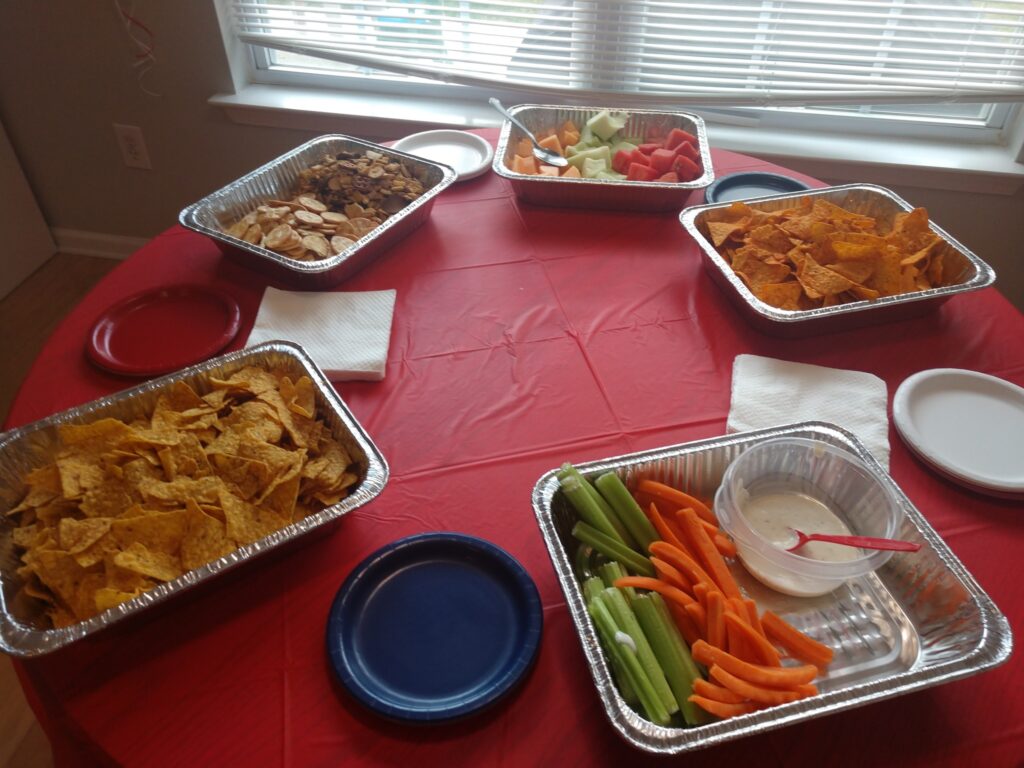 Football party healthy game day food spread of veggies and dip, melons, football crackers and Doritos